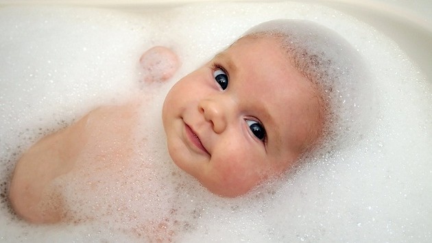 A baby in a bathtub with soap foam.